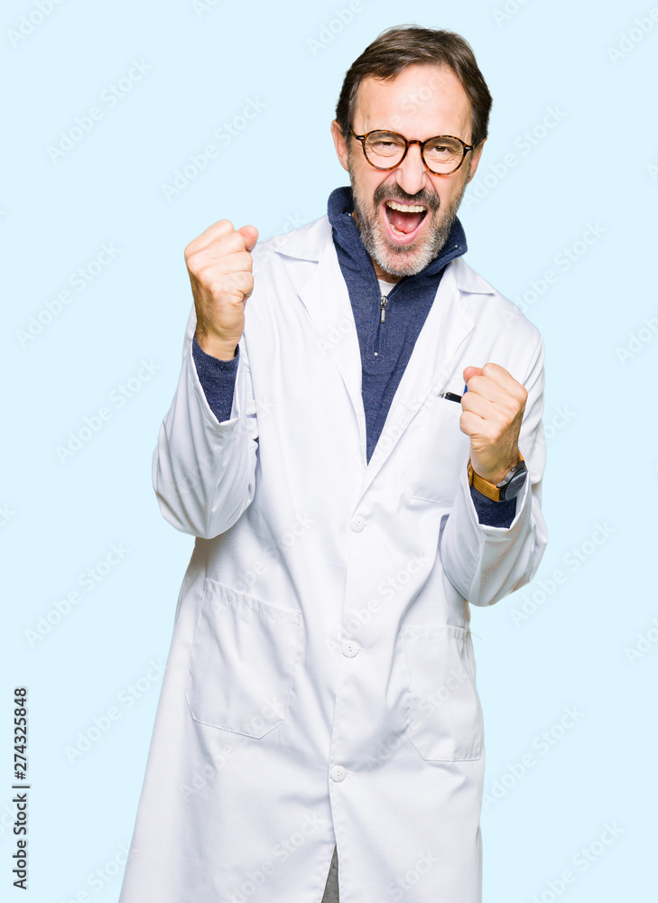 Middle age therapist wearing white coat very happy and excited doing winner gesture with arms raised, smiling and screaming for success. Celebration concept. Middle age therapist wearing white coat very happy and excited doing winner gesture with arms raised, smiling and screaming for success. Celebration concept.