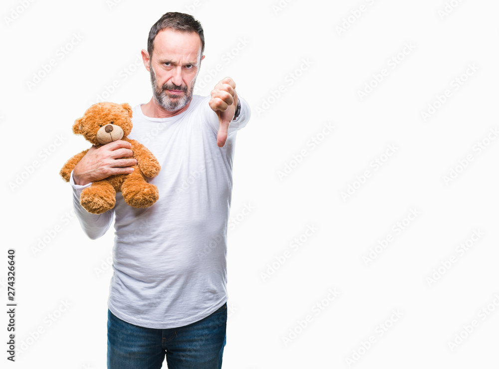 Middle age senior hoary man holding teddy bear over isolated background with angry face, negative sign showing dislike with thumbs down, rejection concept Middle age senior hoary man holding teddy bear over isolated background with angry face, negative sign showing dislike with thumbs down, rejection concept
