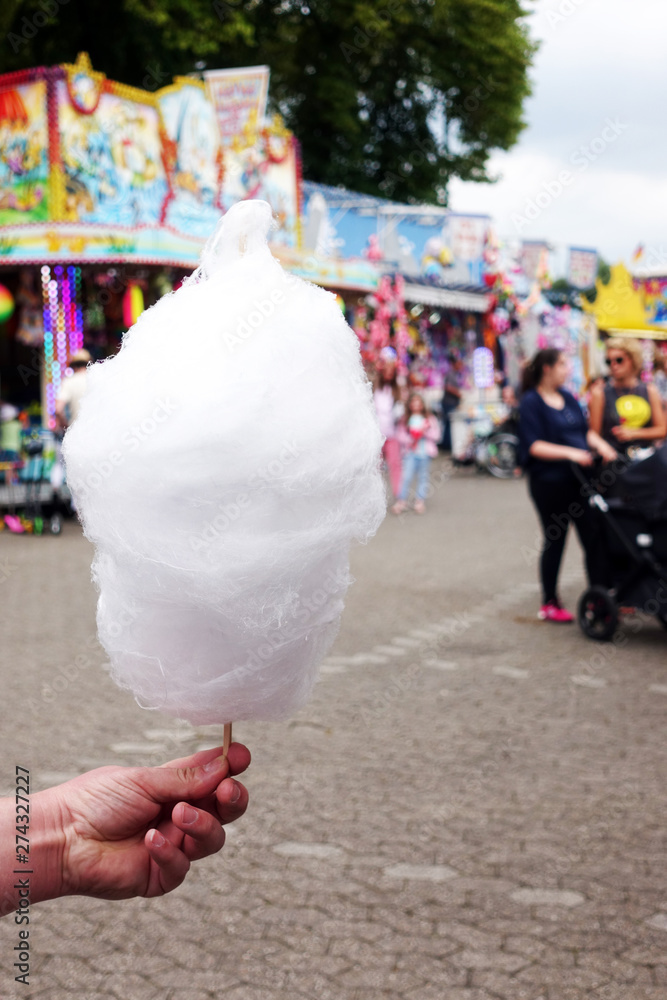 amusement park eating white cotton candy. enjoying a day at amusement park with fresh cotton candy in hand