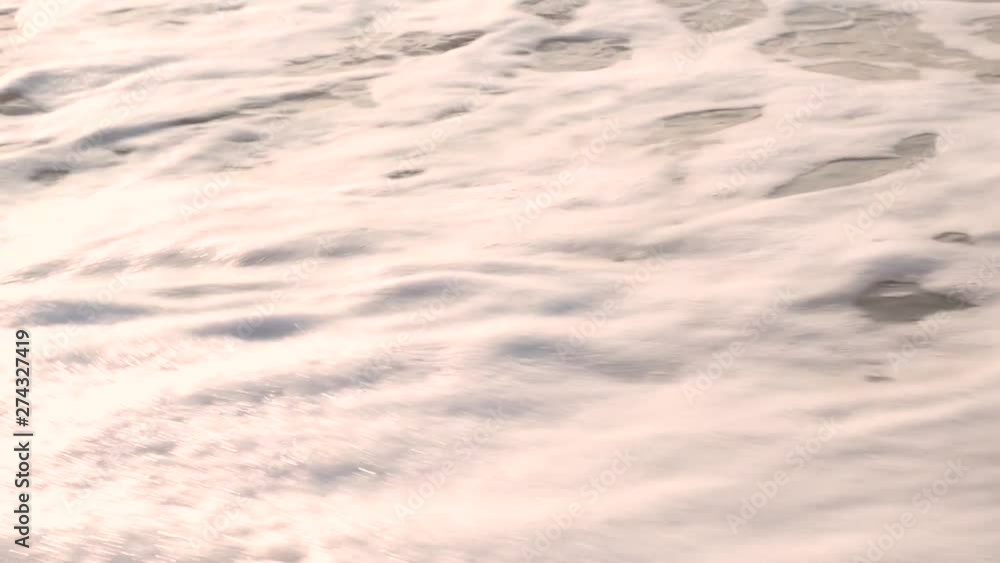 Women's feet leave marks on the wet sand, and the wave washes away with foam. Summer sea Women's feet leave marks on the wet sand, and the wave washes away with foam. Summer sea