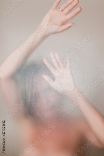 The woman behind the glass washes in the shower stall.