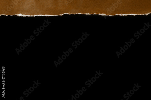torn edge of colored brown paper on a black background, copy space, close-up, blank for designer