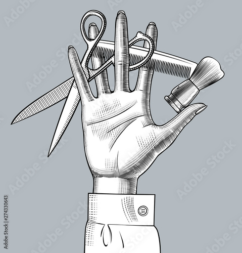Female hand with scissors, brush and comb between fingers
