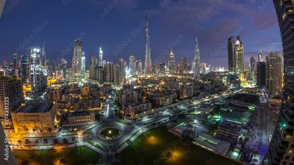 Dubai Downtown skyline night to day transition timelapse with Burj Khalifa and other towers paniramic view from the top in Dubai, United Arab Emirates. Traffic on circle road. Traditional and modern Dubai Downtown skyline night to day transition timelapse with Burj Khalifa and other towers paniramic view from the top in Dubai, United Arab Emirates. Traffic on circle road. Traditional and modern
