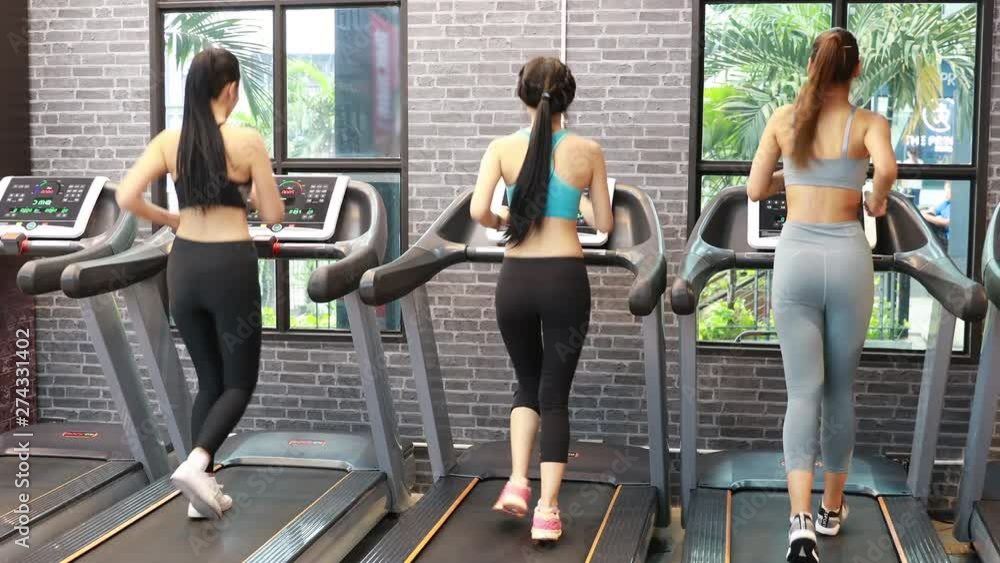 Group Young beautiful woman asian running on a treadmill at gym. Fitness and healthy lifestyle concept. Rear view of girl in sportswear jogging exercise. real time