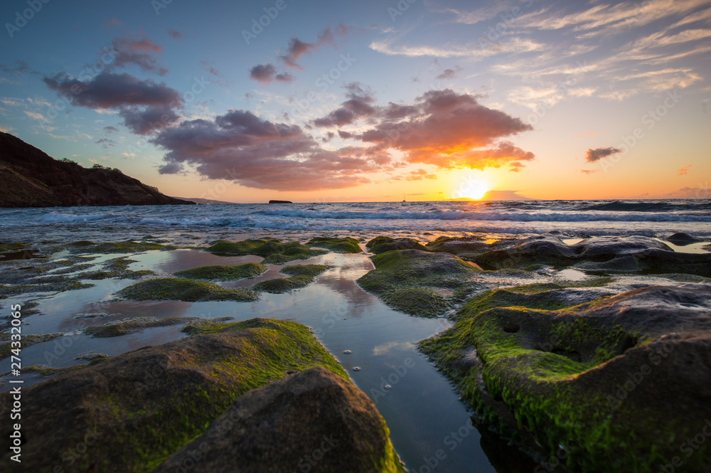 Sunset over mossy rocks in Maui