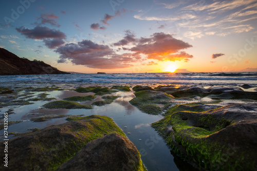 Sunset over mossy rocks in Maui