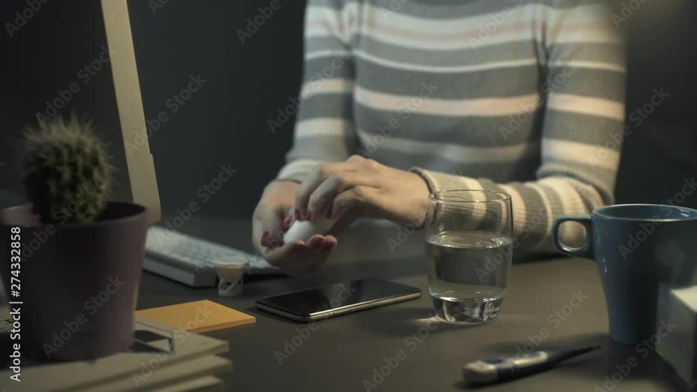 Woman with flu taking an aspirin at night Woman with flu taking an aspirin at night