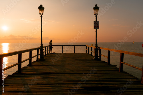 Wooden dock  sea and fisherman in the sunrise. Beautiful summer scenery