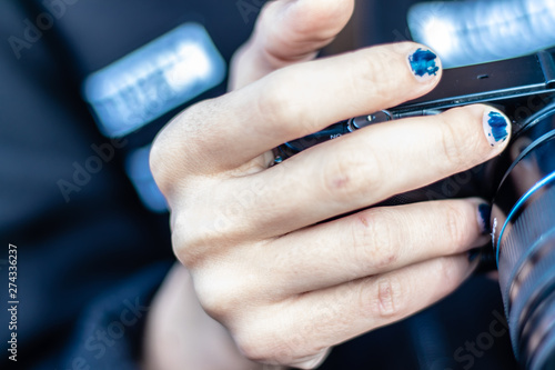 a girl with scratched nail polish holding a camera from sides