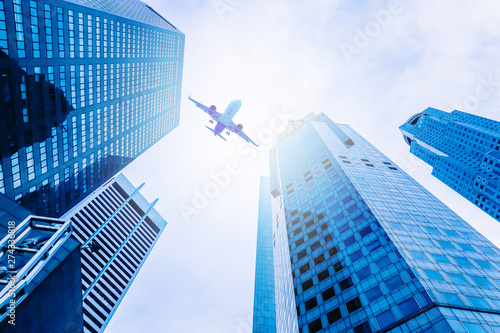 Airplane flying over modern glass and steel office buildings in singapore