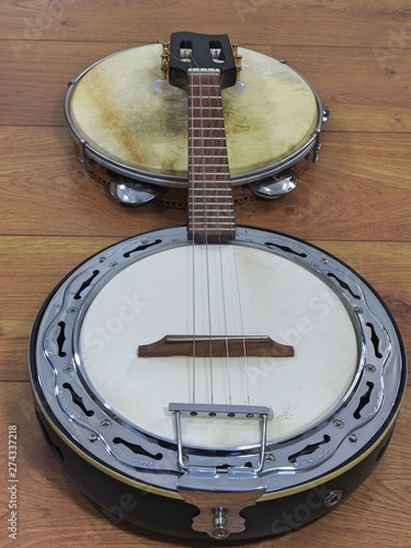 Two Brazilian musical instruments: samba banjo (strings) and pandeiro (tambourine) on a wooden surface. They are widely used to accompany samba, the most famous Brazilian rhythm.