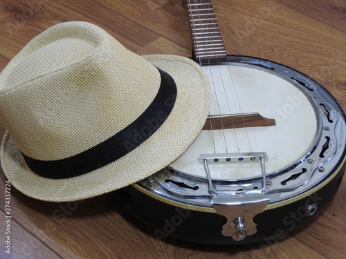 A samba banjo (a Brazilian string musical instrument) and a samba player (sambista) hat on a wooden surface. The instrument is widely used to accompany samba, the most popular Brazilian rhythm.