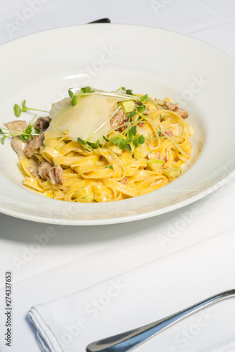 Tagliatelle pasta with cheese and chicken meat served on a white plate