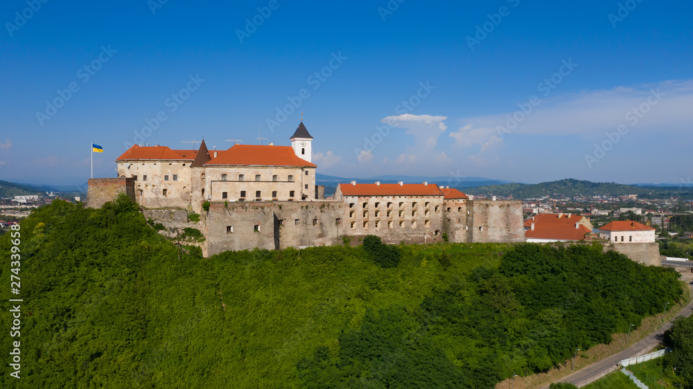 Picturesque view to the Palanok Castle with the red roofs under the blue sky in Mukachevo, Transcarpathian region in Ukraine. Horizontal outdoors shot.