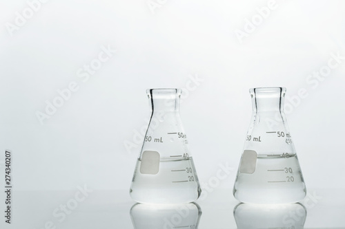 two glass science laboratory flask with clear water on white background