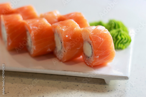 Fresh rolls philadelphia and wasabi sauce on rectangular white plate close-up