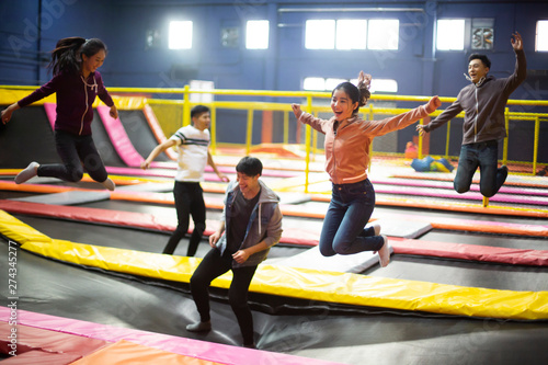 Happy young friends jumping on trampoline