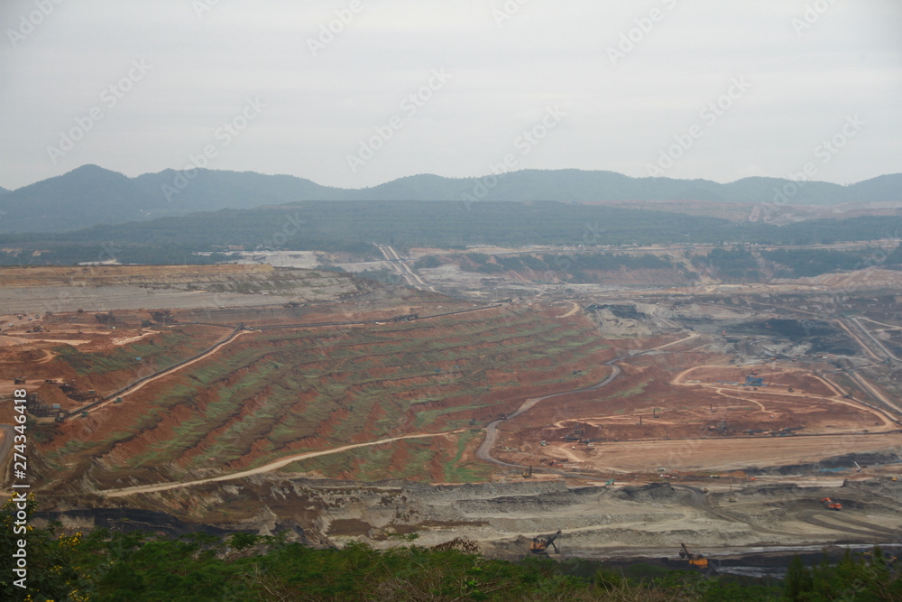 Lignite coal mining industry as a raw materials for coal fire electric power plant. There are excavators and transport trucks are working within the lignite coal mine.