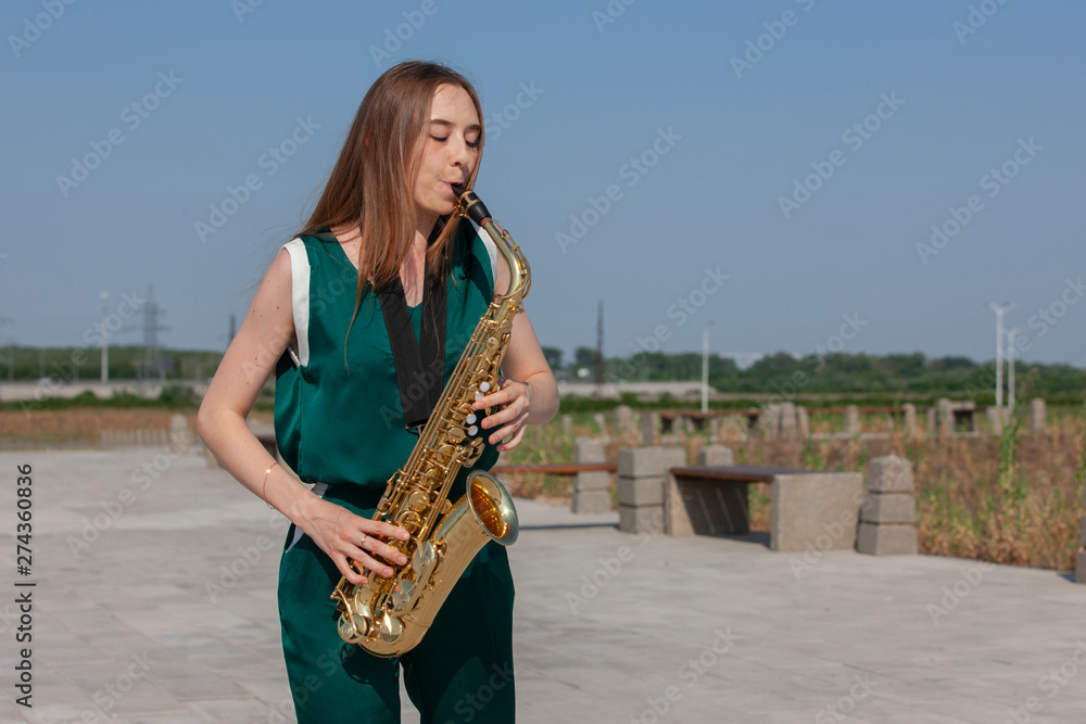 Naklejka premium Young woman with saxophone with nature background