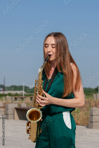 Sticker Beautiful brunette plays the saxophone in the park
