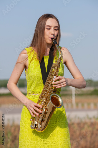 Canvas Print Beautiful brunette plays the saxophone in the park