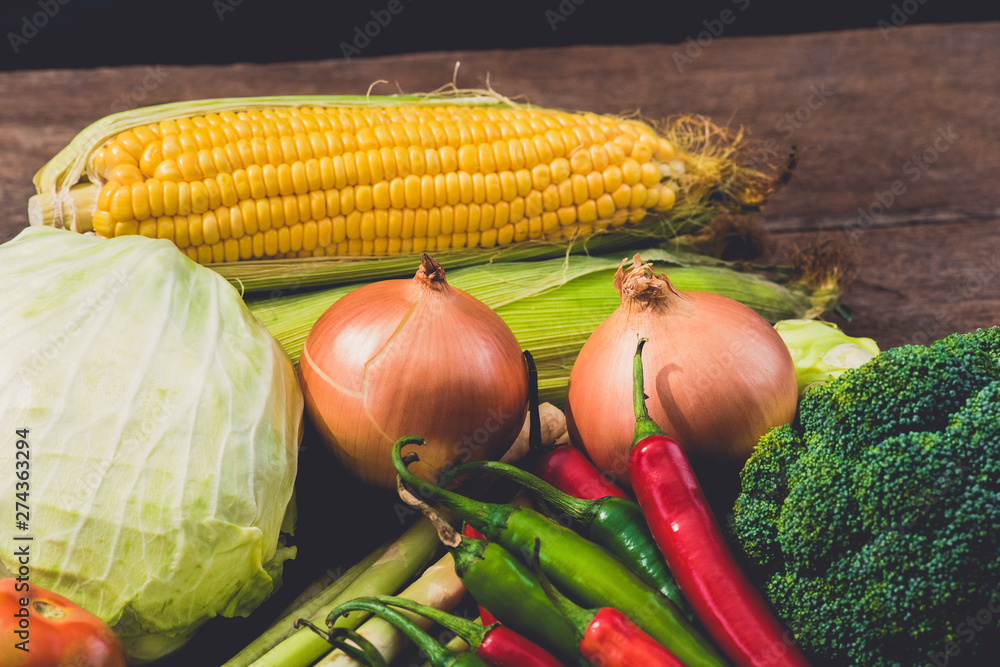 Fresh yellow corn with cobs and various kinds of vegetables as background on rustic wooden table Fresh yellow corn with cobs and various kinds of vegetables as background on rustic wooden table
