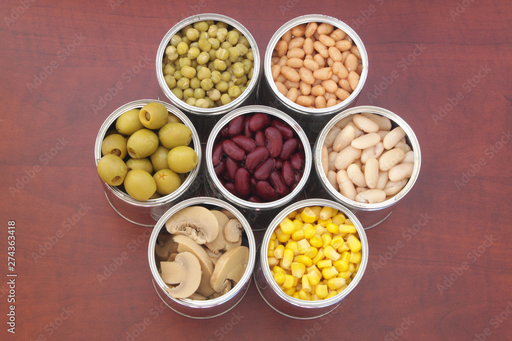 Seven tin cans with canned food on wooden background, top view Seven tin cans with canned food on wooden background, top view