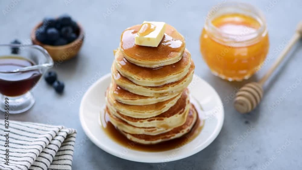 Rotating stack of delicious pancakes with honey, maple syrup and butter Rotating stack of delicious pancakes with honey, maple syrup and butter