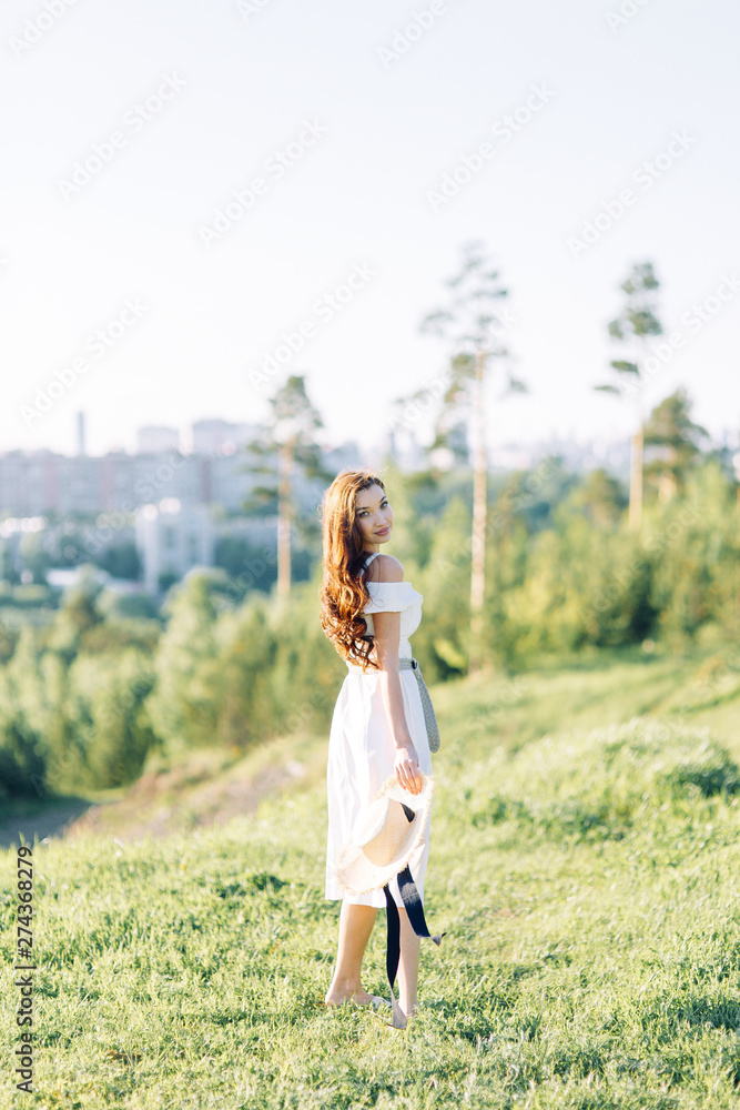  Beautiful girl in white dress and hat. Summer photo shoot in the Park at sunset.