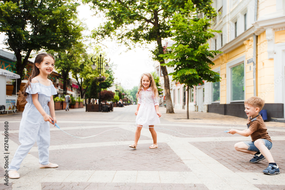 Little friends are walking around the city. Play and have fun. Three jump over the rope.
