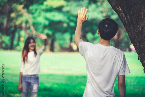 Fényképezés Young people, man and woman greeting or saying goodbye by waving hands in the park