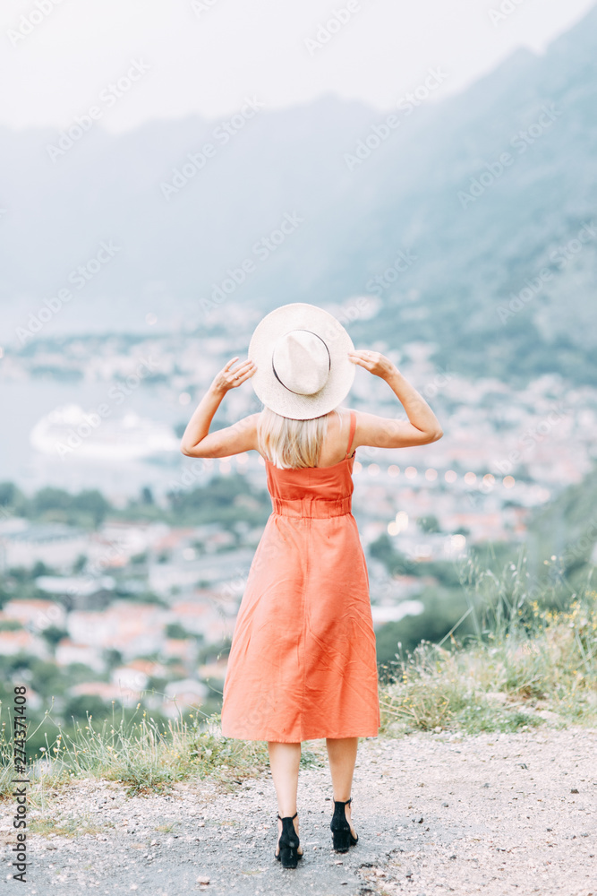 Summer photo shoot at sunset in Kotor, Montenegro. Beautiful girl in red dress and hat.