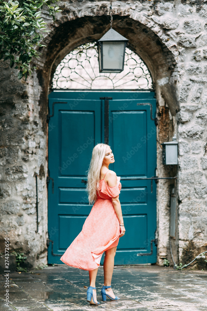  A beautiful girl in a red dress. Photo shoot on the evening streets of Kotor.