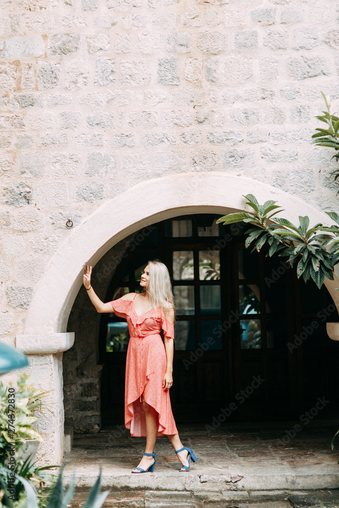  A beautiful girl in a red dress. Photo shoot on the evening streets of Kotor.