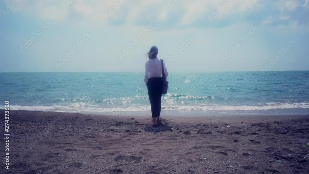 business lady actively walks on the beach, goes into the water and stopped raises his hands up . concept vacation. tonted image business lady actively walks on the beach, goes into the water and stopped raises his hands up . concept vacation. tonted image