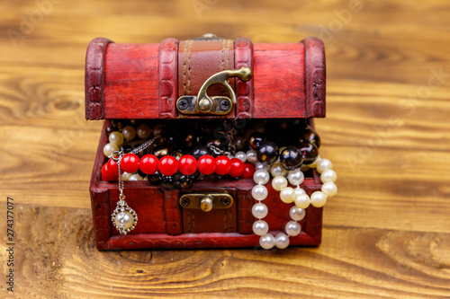 Vintage treasure chest full of jewelry and accessories on wooden background