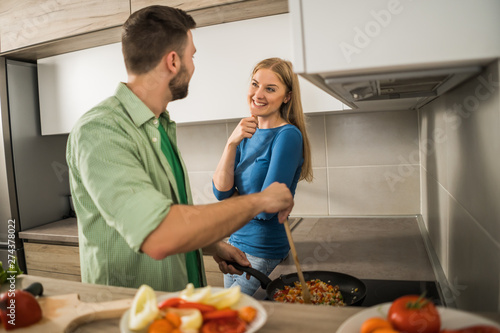 Young couple is preparing meal in their kitchen. 