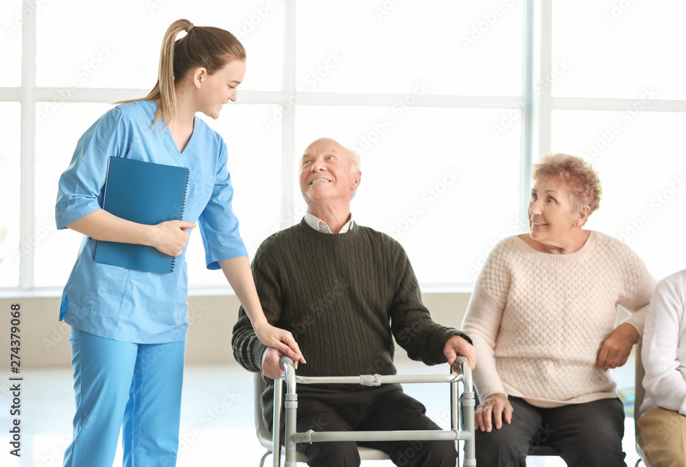 Young caregiver with group of senior people in nursing home Young caregiver with group of senior people in nursing home