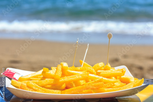 Fried french fries on the beach against the background of the sea