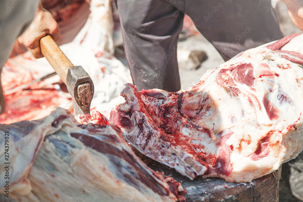 Processing fresh meat. Butcher with a axe in hand separating meat