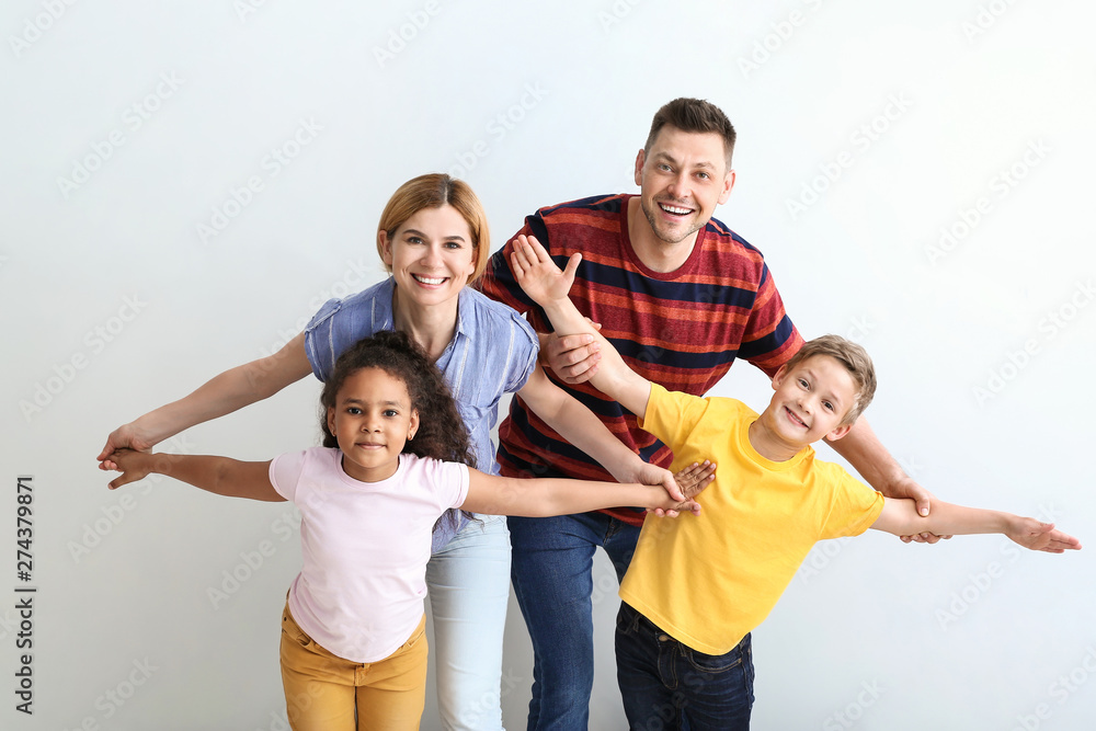 Happy couple with little adopted children on light background Happy couple with little adopted children on light background