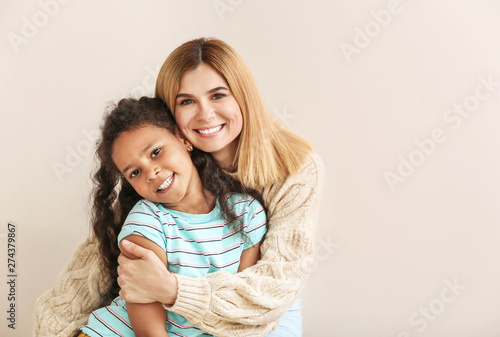 Happy woman with little adopted African-American girl on white background photo