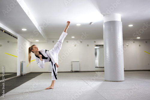 Cute girl with dyed blonde hair practicing martial art of taekwondo