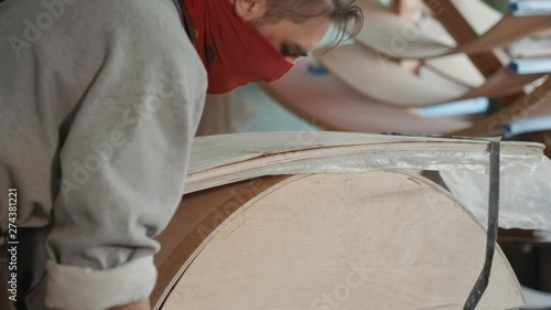 Worker glues veneer on a wooden part apt glue press machine plywood workshop factory. Craftman man equipment