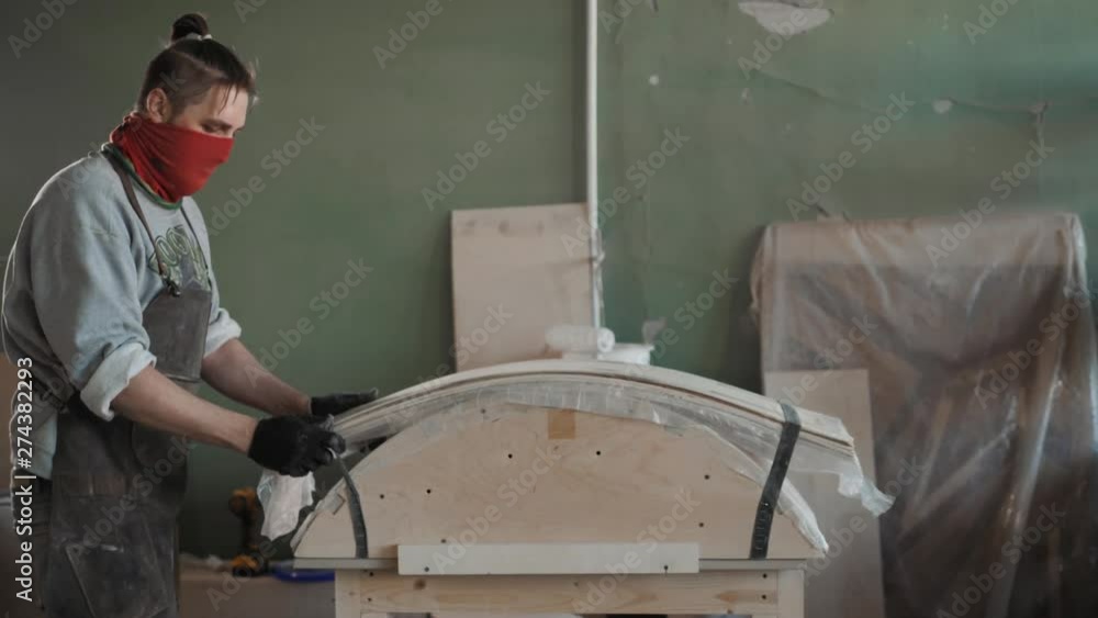 Worker glues veneer on a wooden part apt glue press machine plywood workshop factory. Craftman man equipment Worker glues veneer on a wooden part apt glue press machine plywood workshop factory. Craftman man equipment
