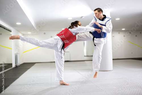 A Guy and a girl in close taekwondo combat training