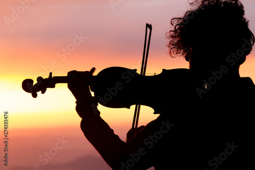 Silhouette of a woman with a violin at sunset.