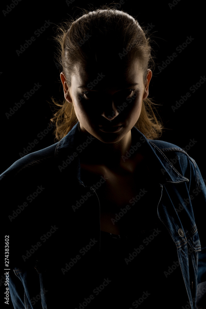 Silhouette of young unknown woman on black background