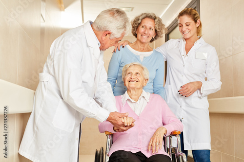 Chef doctor consoles senior woman in wheelchair